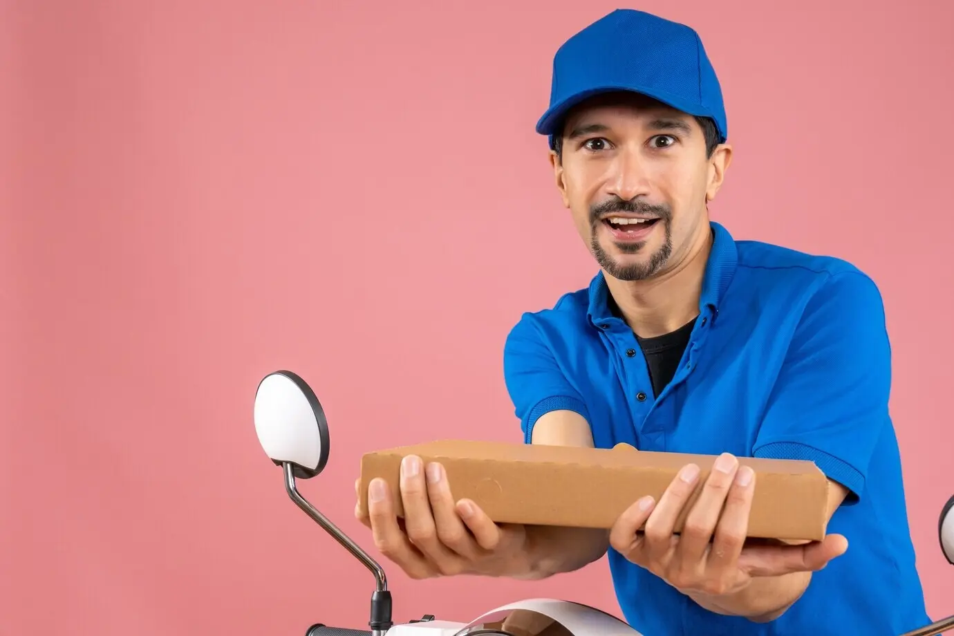 Поясной кадр уверенного курьера-мужчины в головном уборе, сидящего на скутере и держащего заказ.